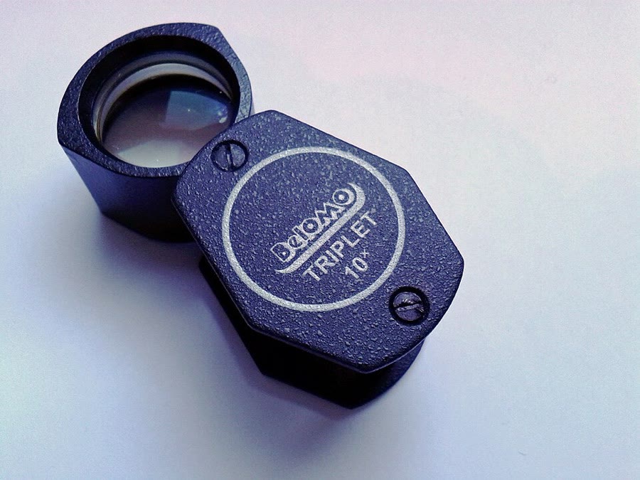 A folding 10X triplet hand lens seen from above